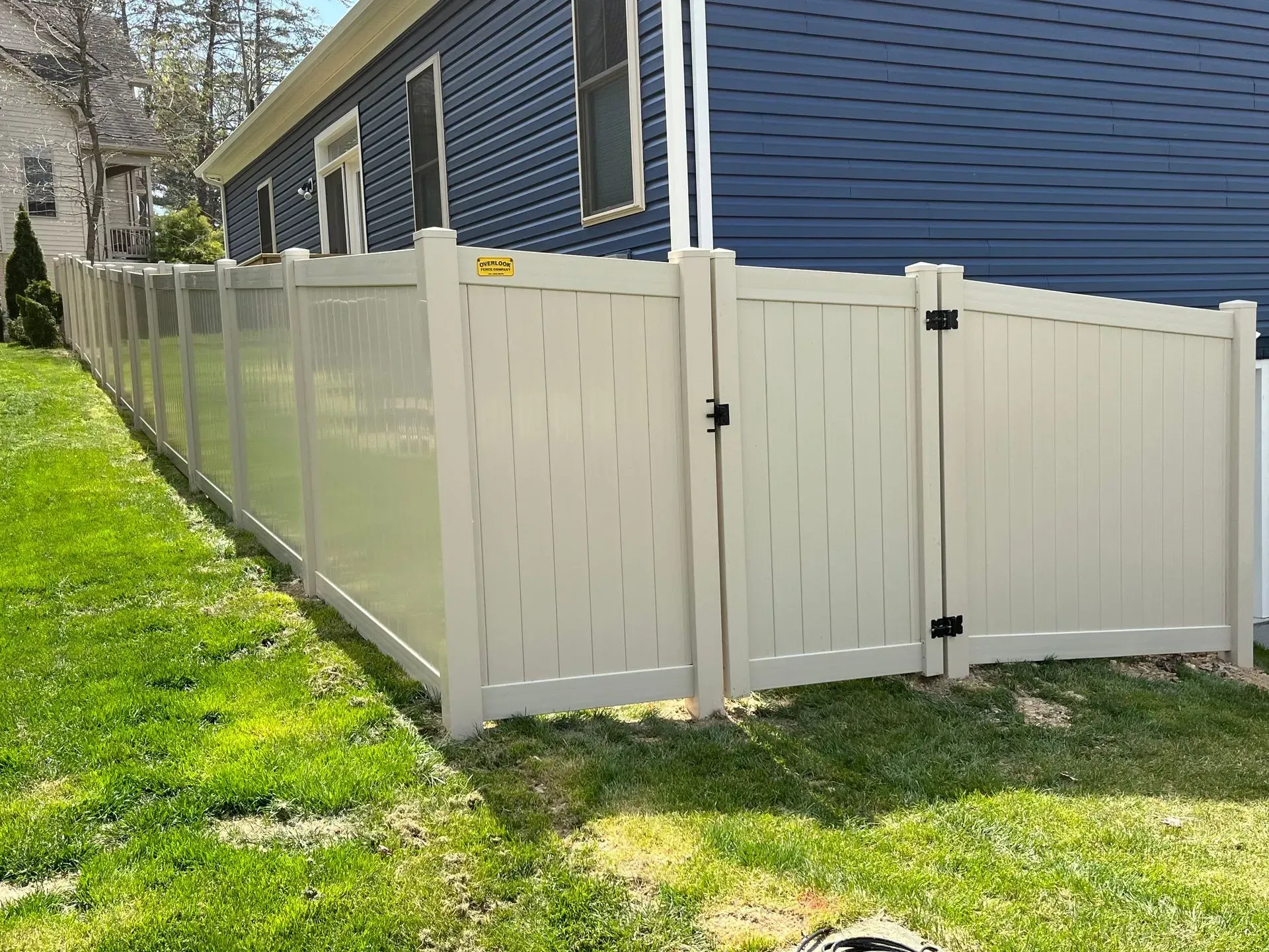 A white fence is in front of a blue house.