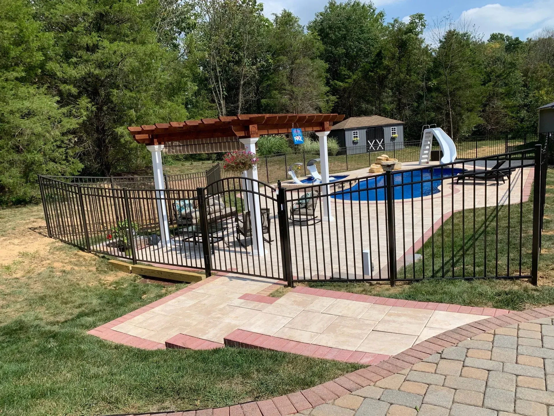 A fence surrounds a swimming pool in a backyard.