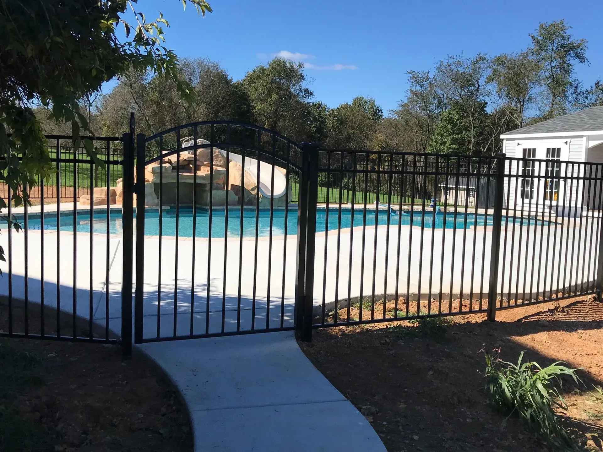 A black fence surrounds a large swimming pool