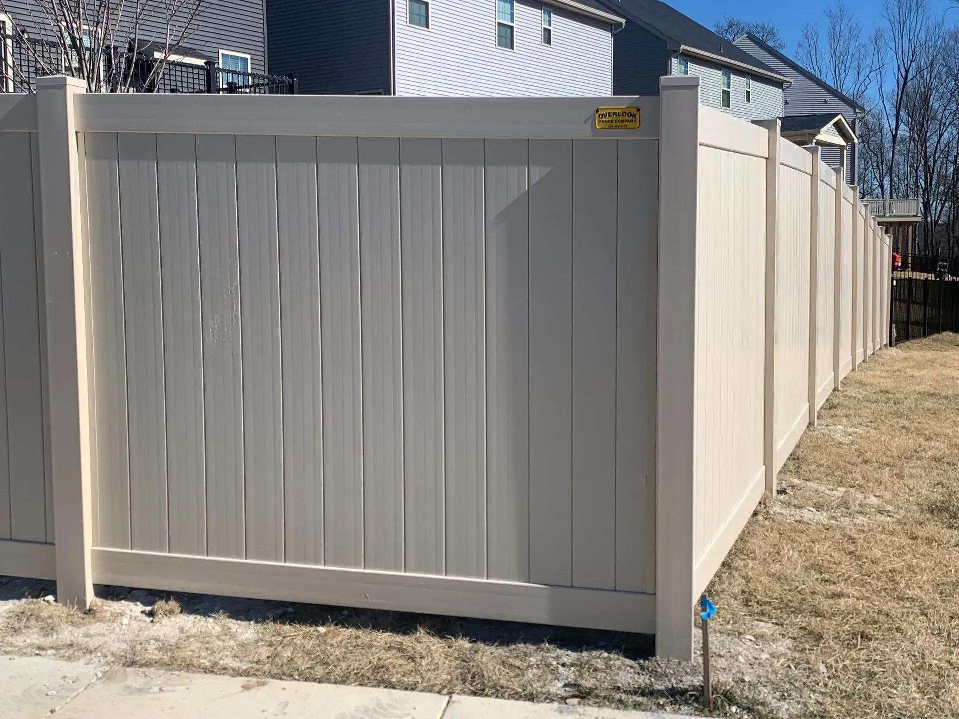 A white vinyl fence is sitting next to a sidewalk in front of a house.