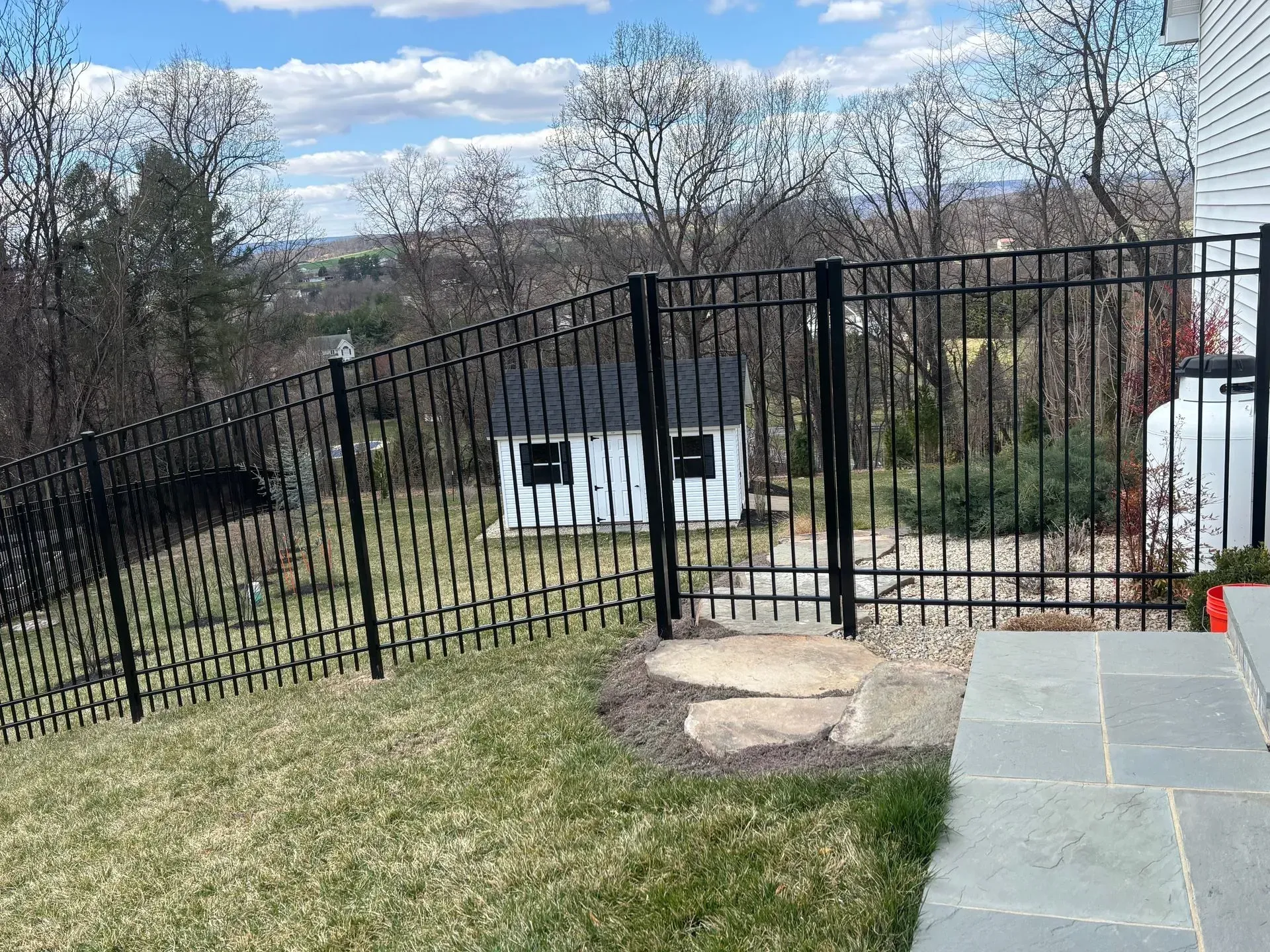 A black metal fence surrounds a lush green yard.