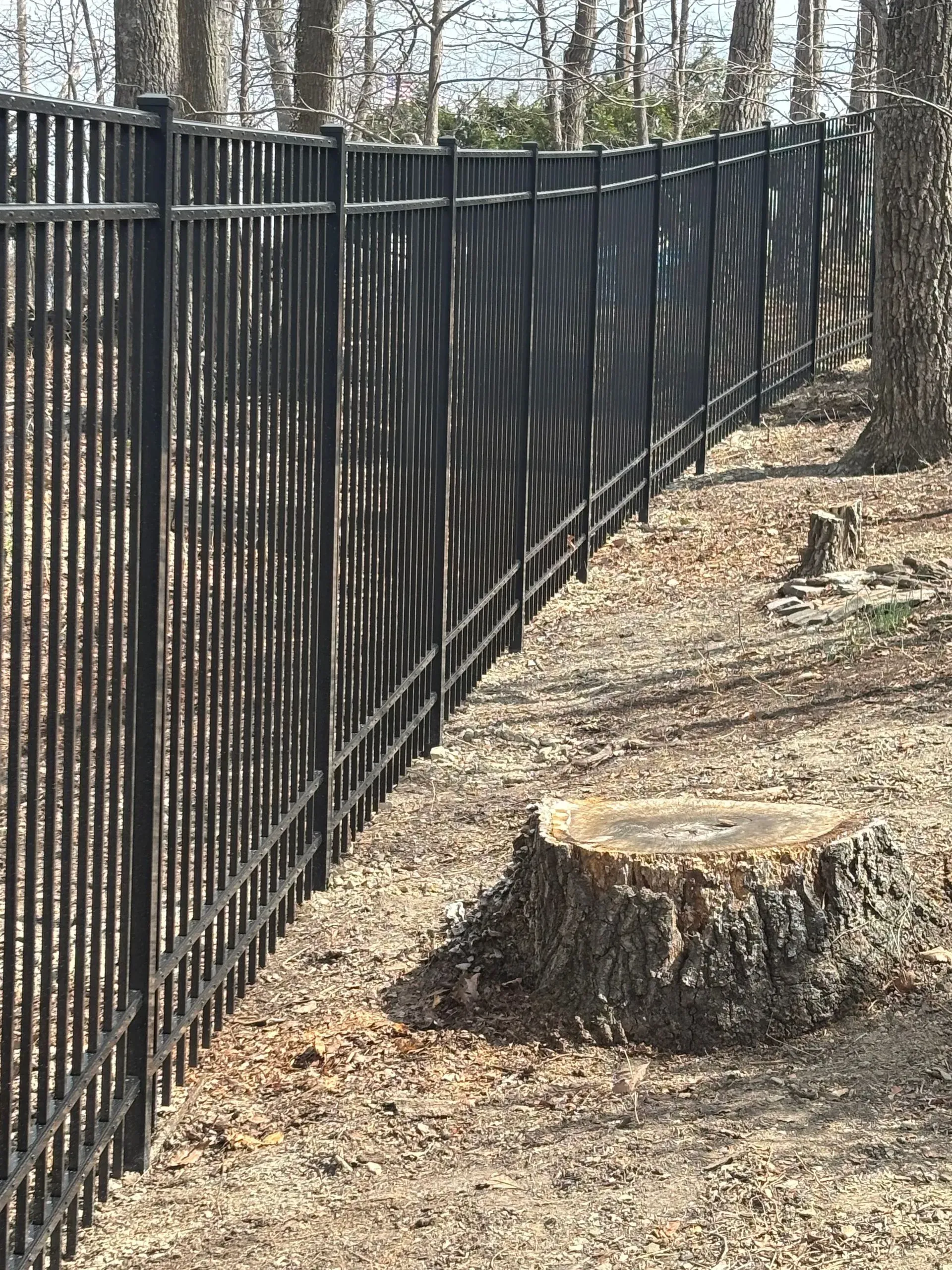 A black fence with a tree stump in the middle of it.