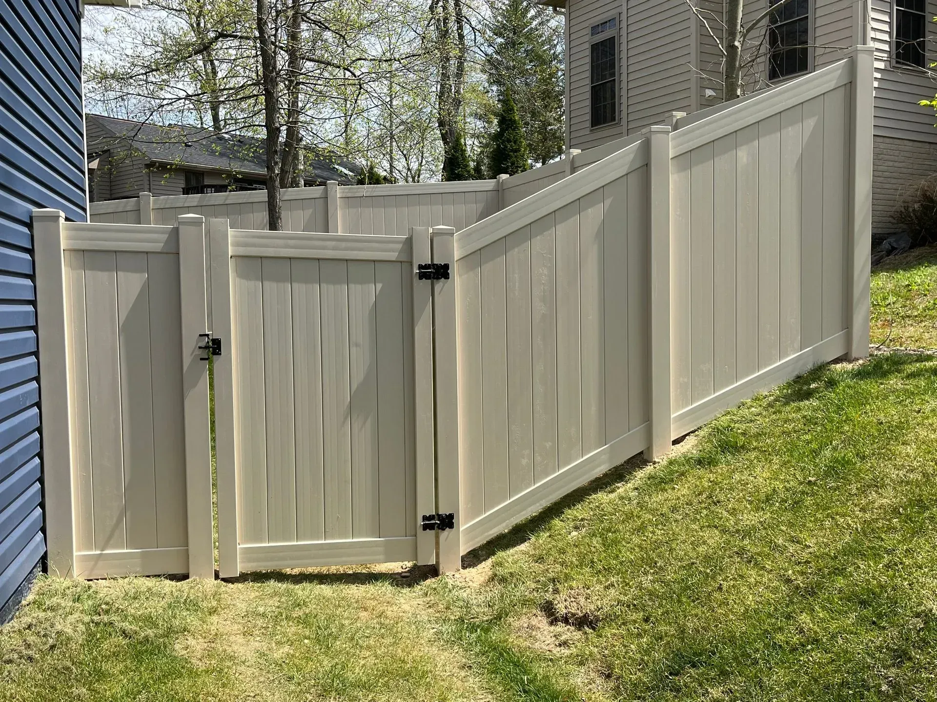 A white vinyl fence with a gate in front of a house.