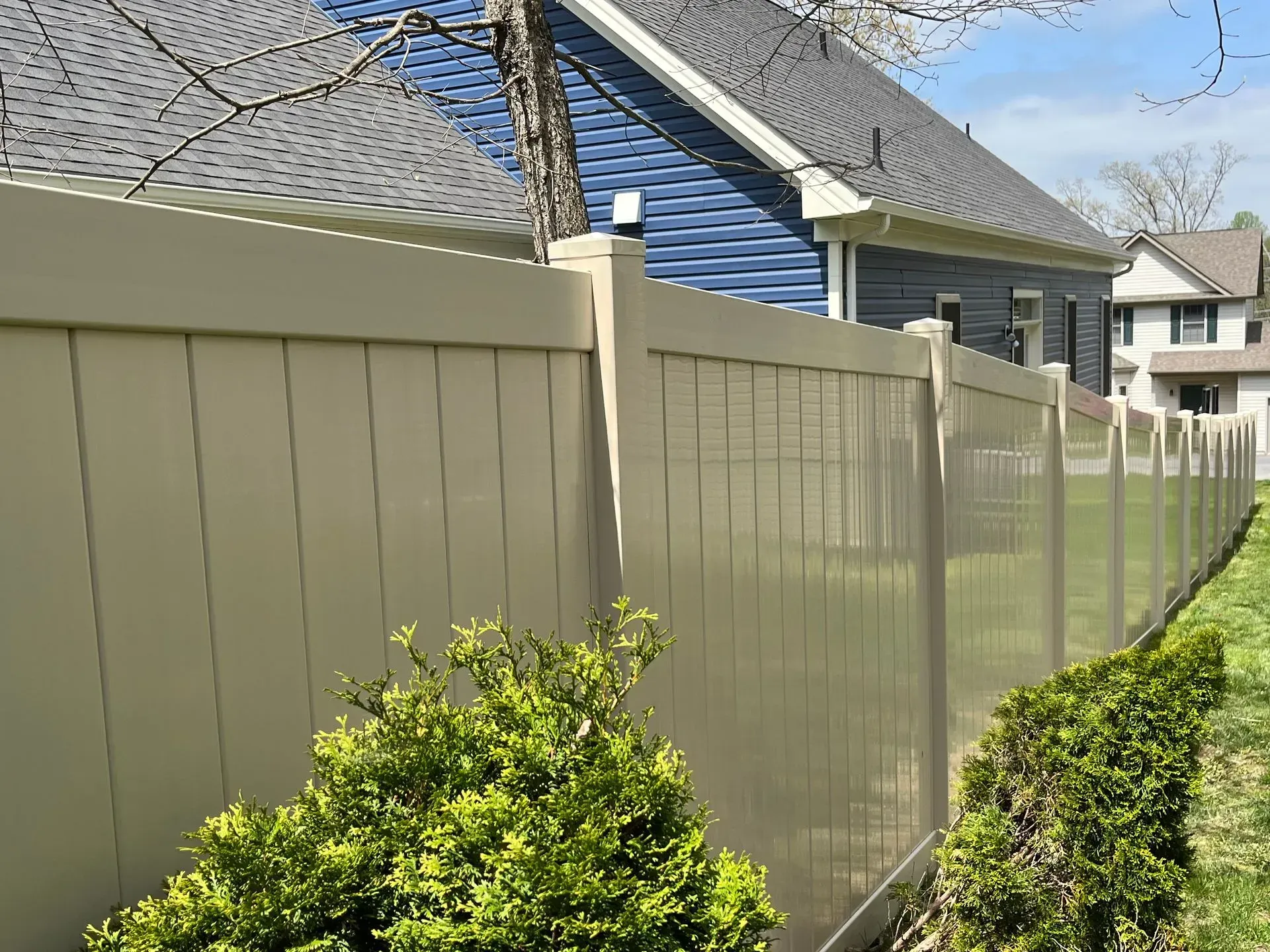 A white fence surrounds a lush green yard in front of a house.