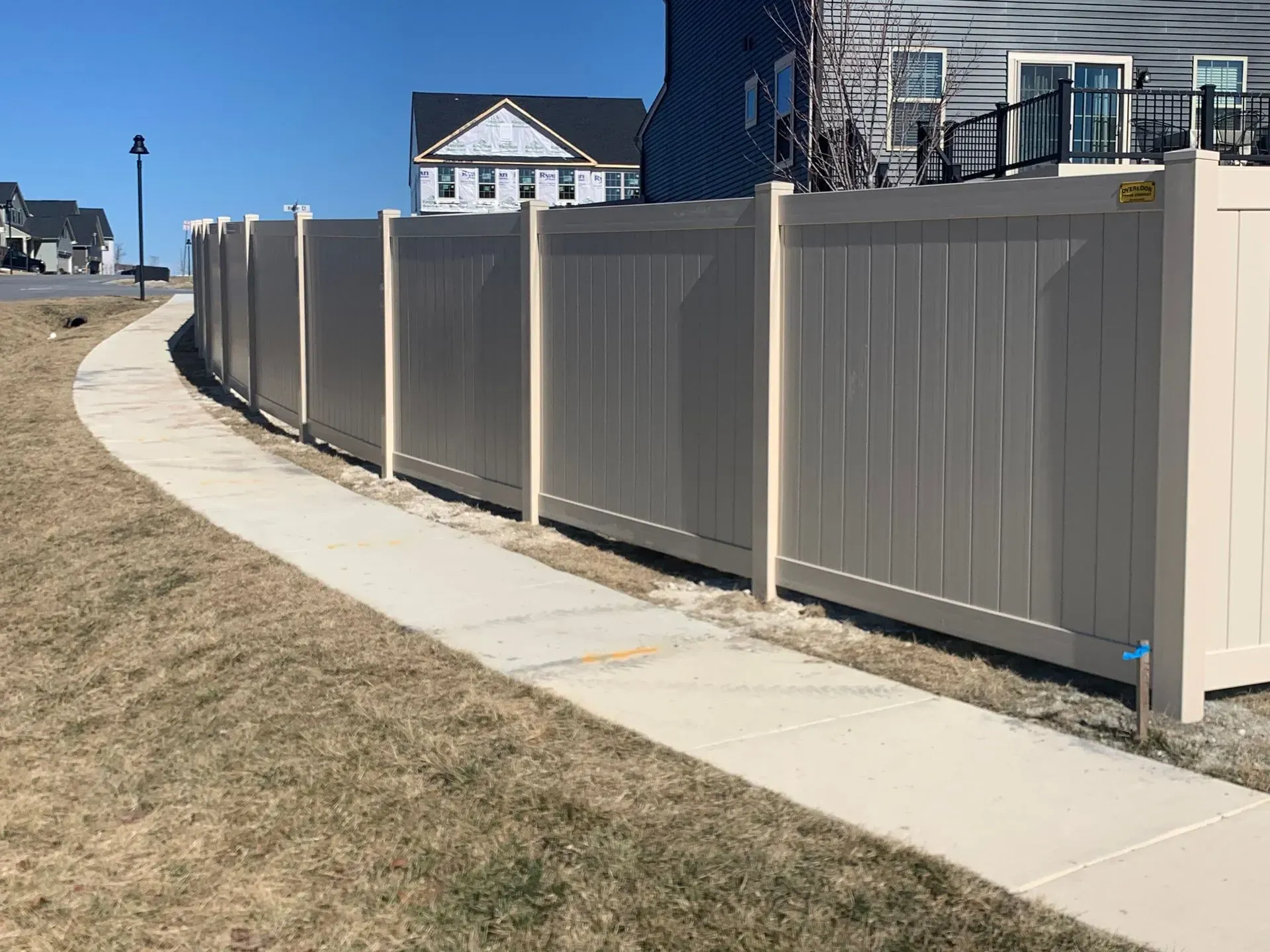 A white fence along a sidewalk next to a house.