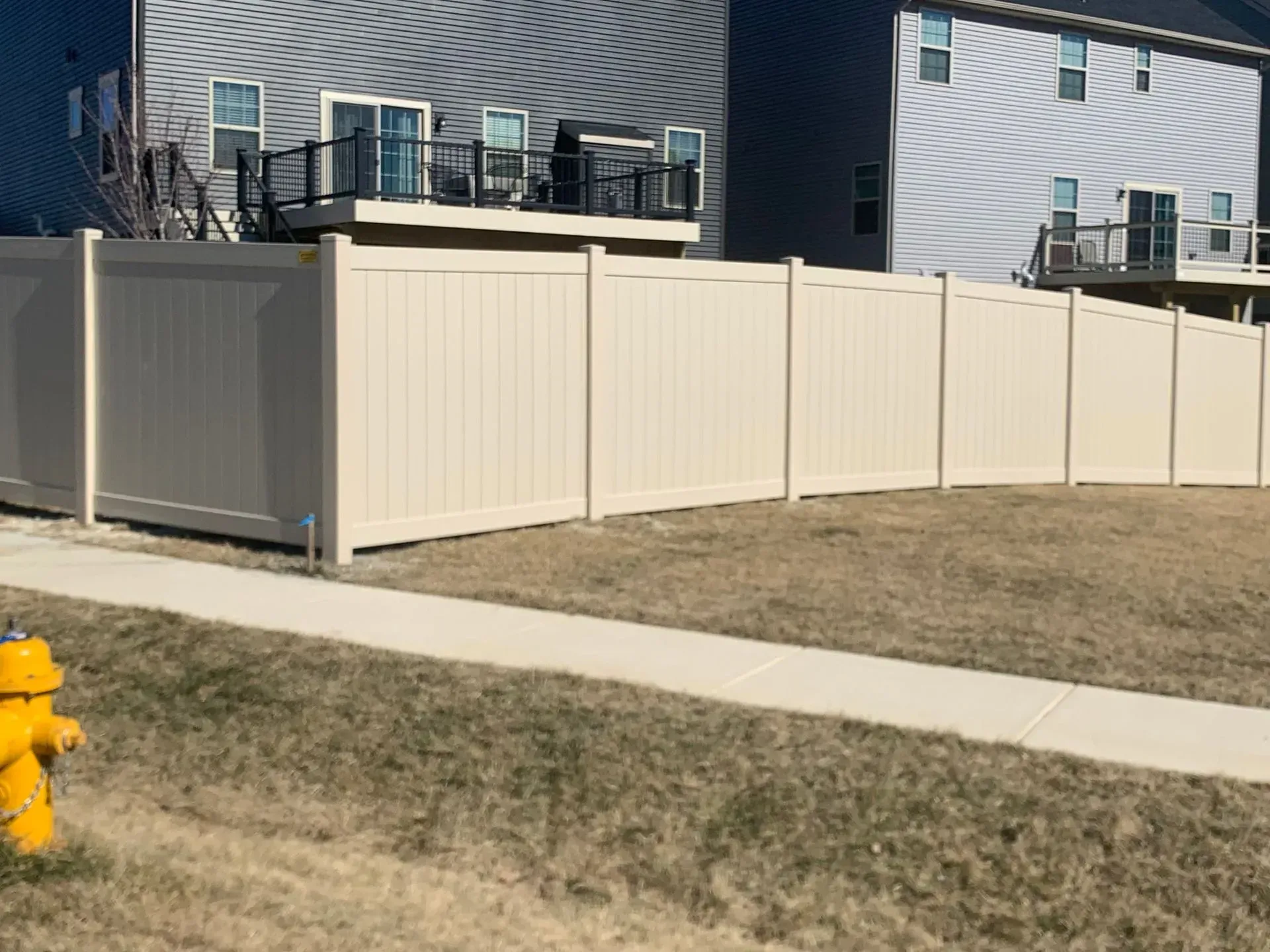 There is a fire hydrant in front of a white fence.