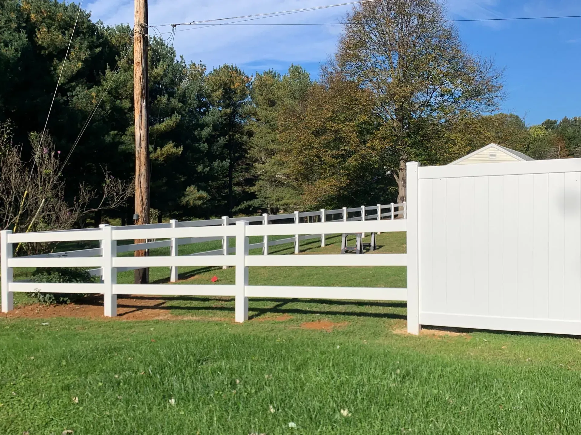 A white fence is in the middle of a grassy field.