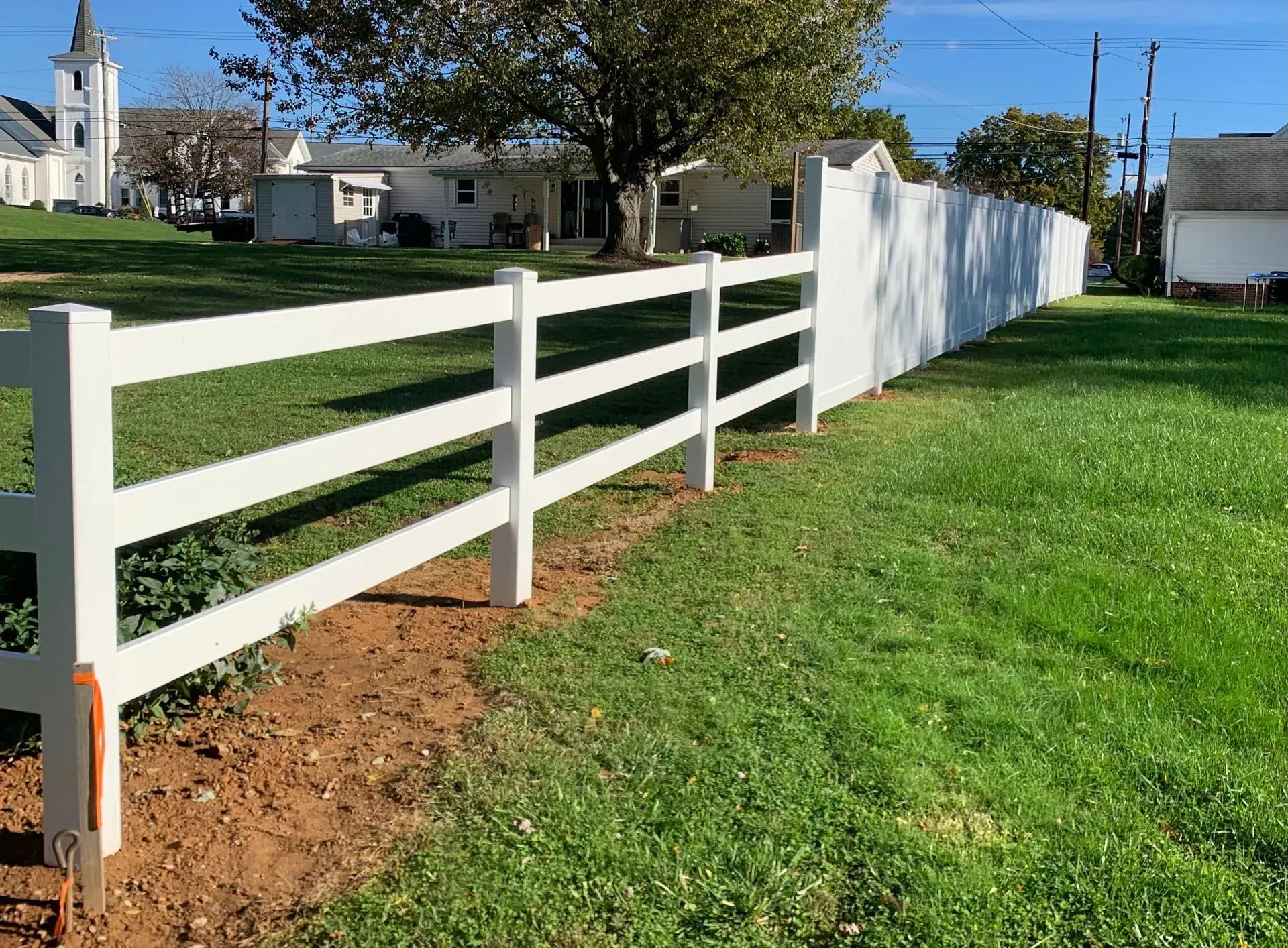 A white fence surrounds a lush green field.