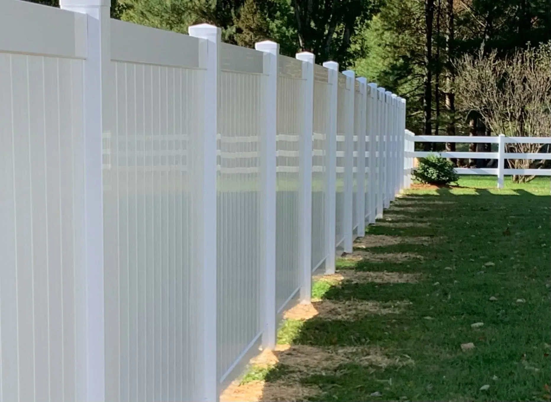 A white fence is sitting in the middle of a lush green field.