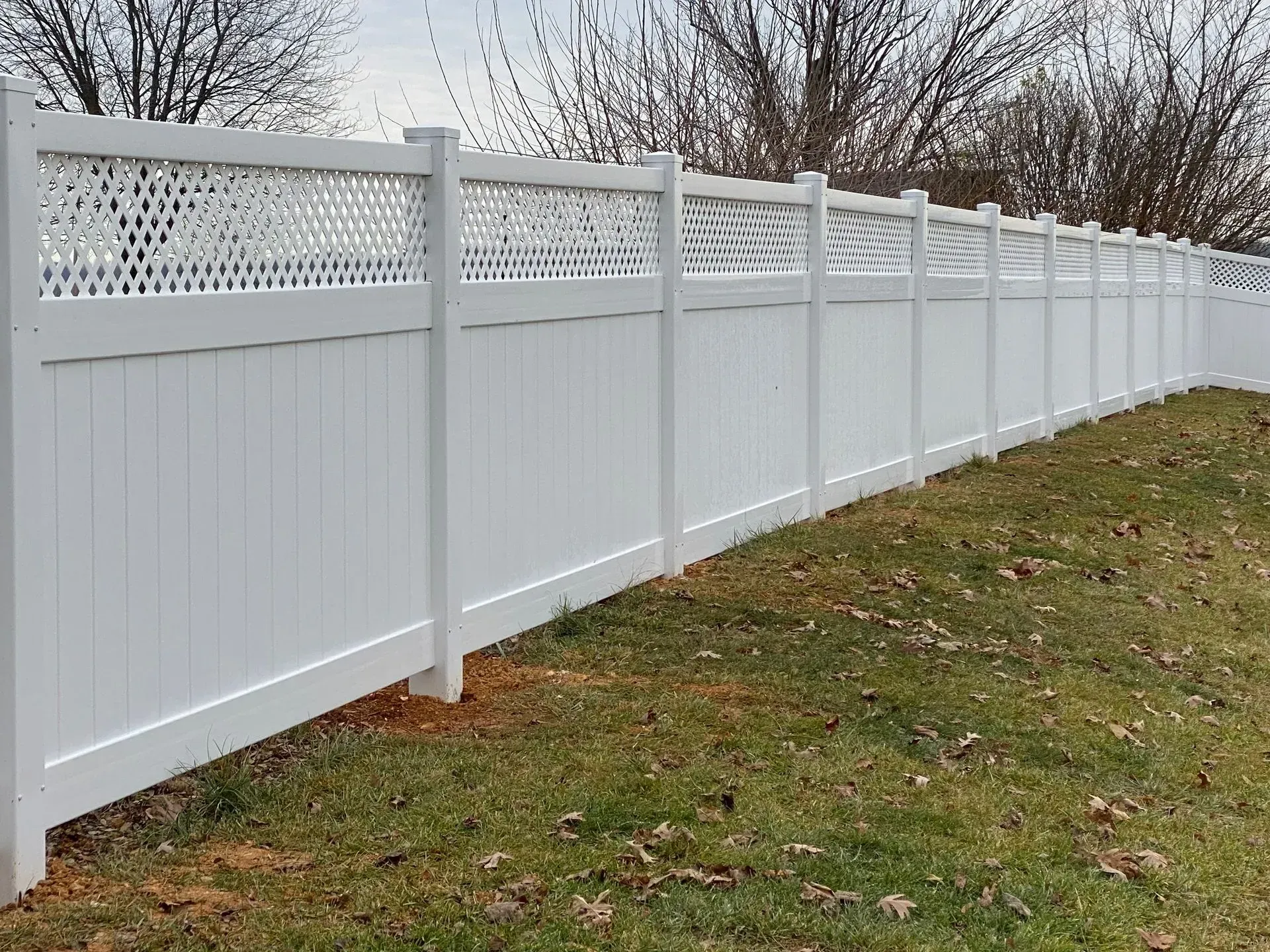 A white fence is sitting on top of a lush green field.