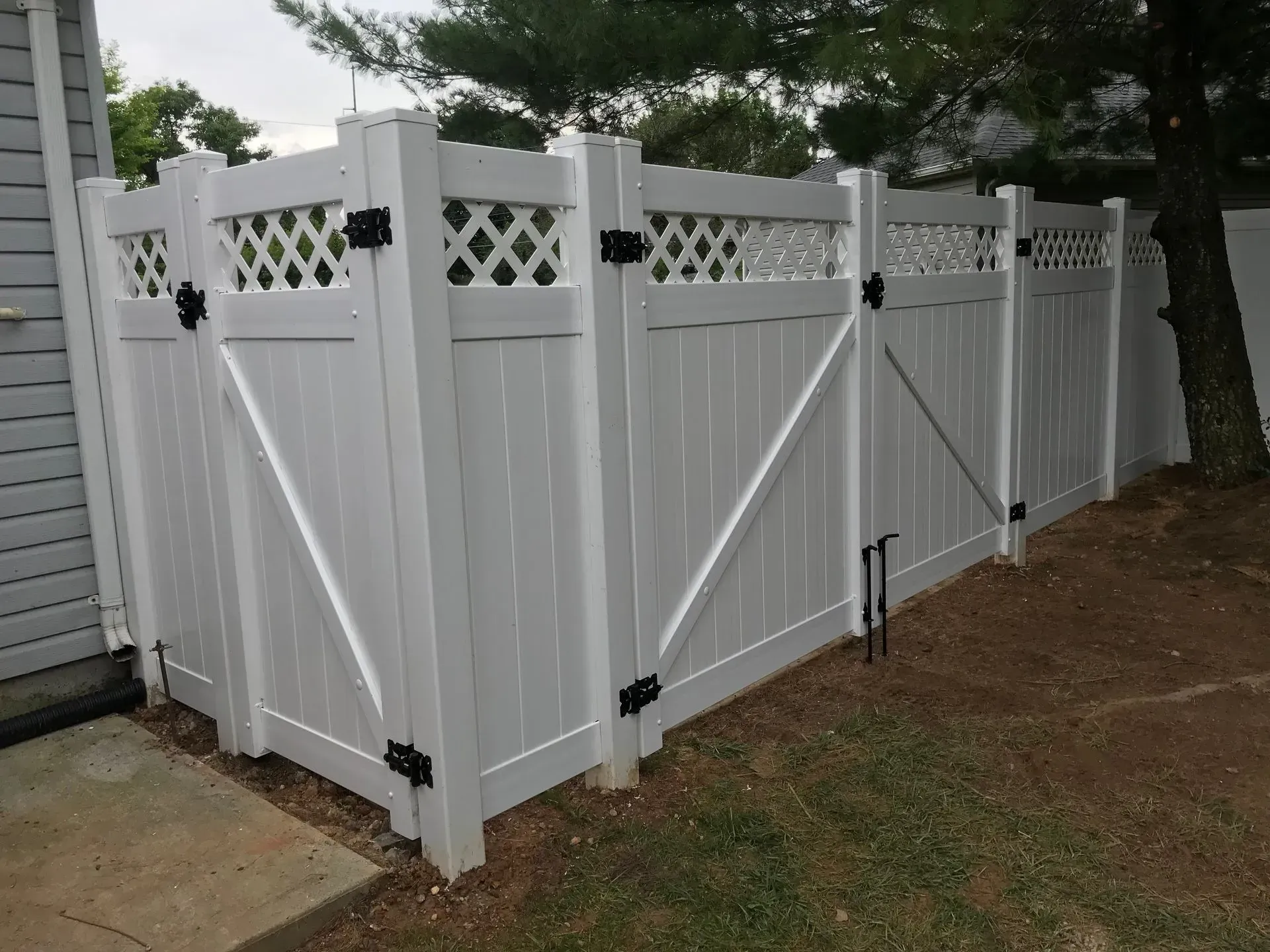 A white fence with a black gate in front of a house
