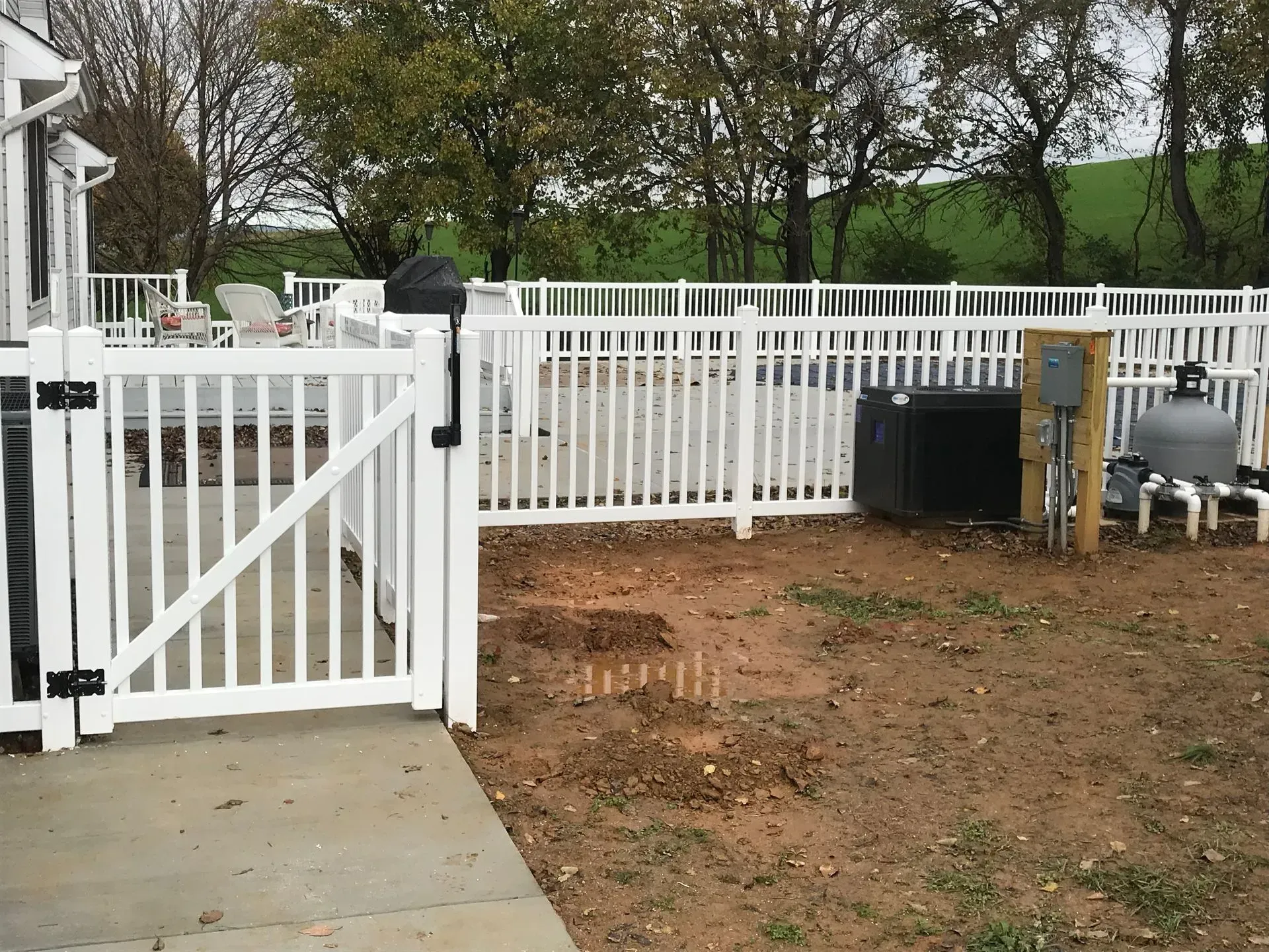 A white fence with a gate in the backyard of a house.