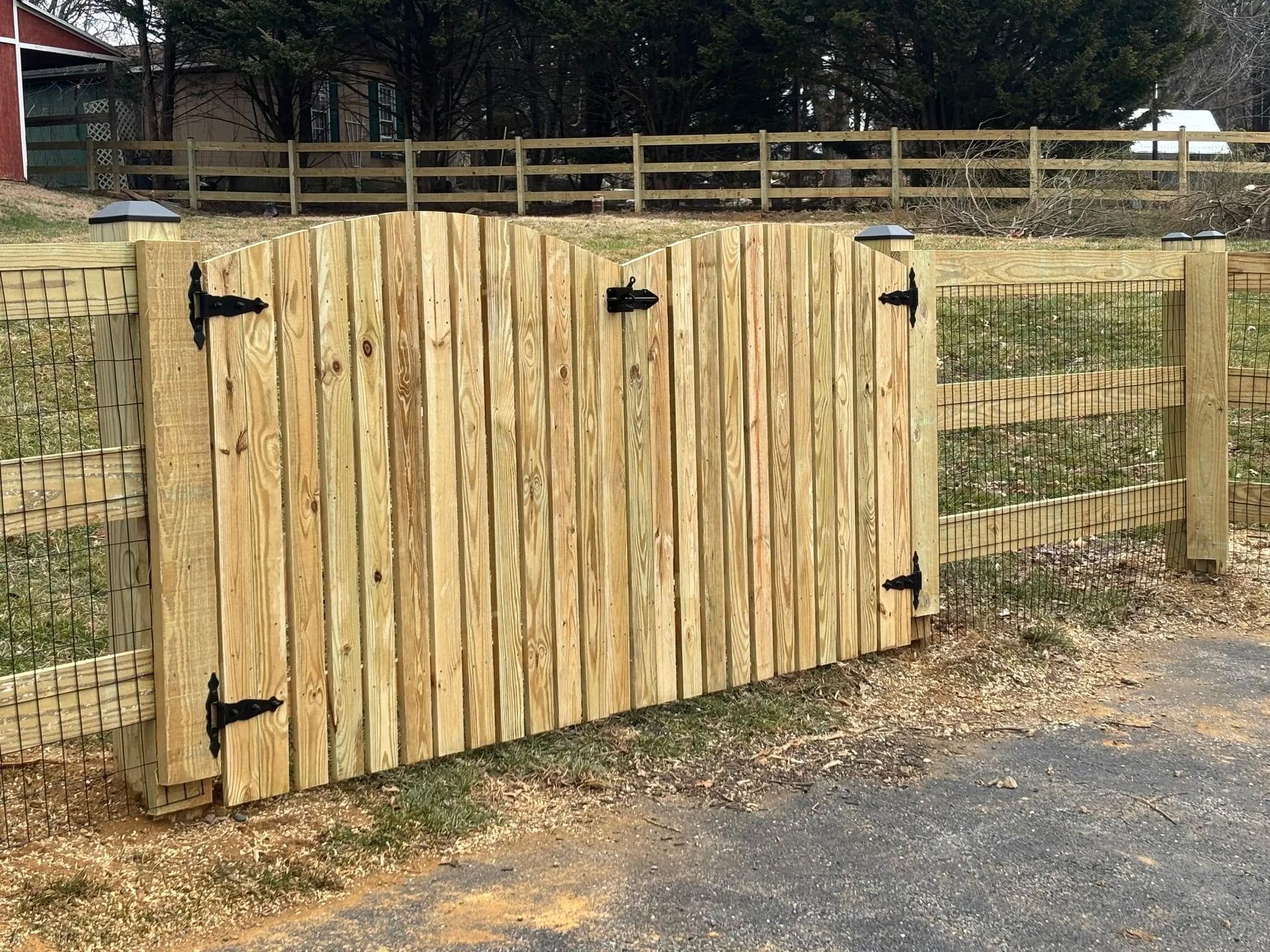A wooden fence with a gate in the middle of a field.