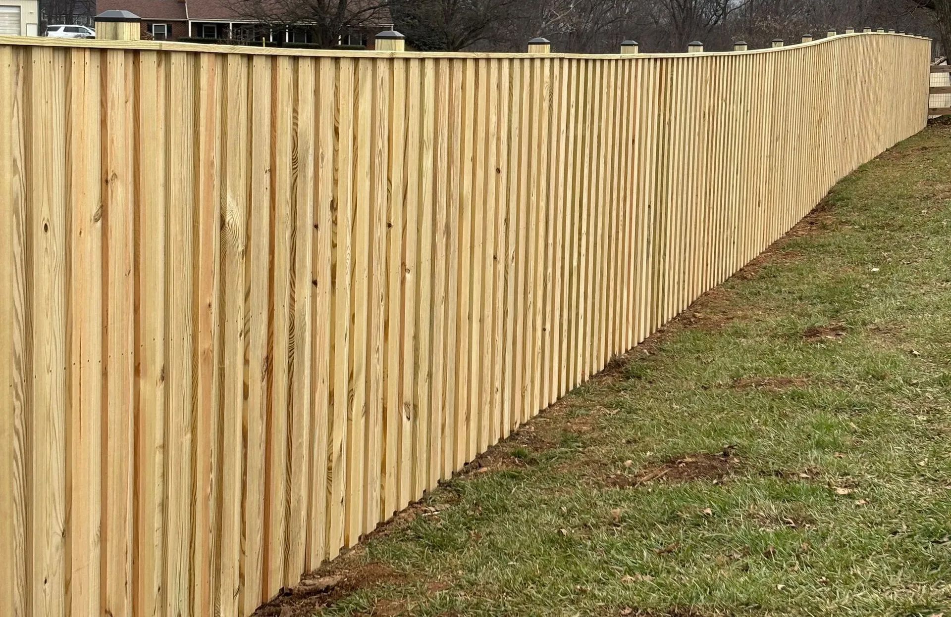 A long wooden fence is sitting in the middle of a grassy field.