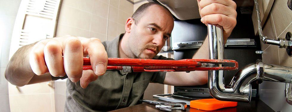 plumber with wrench fixing a sink