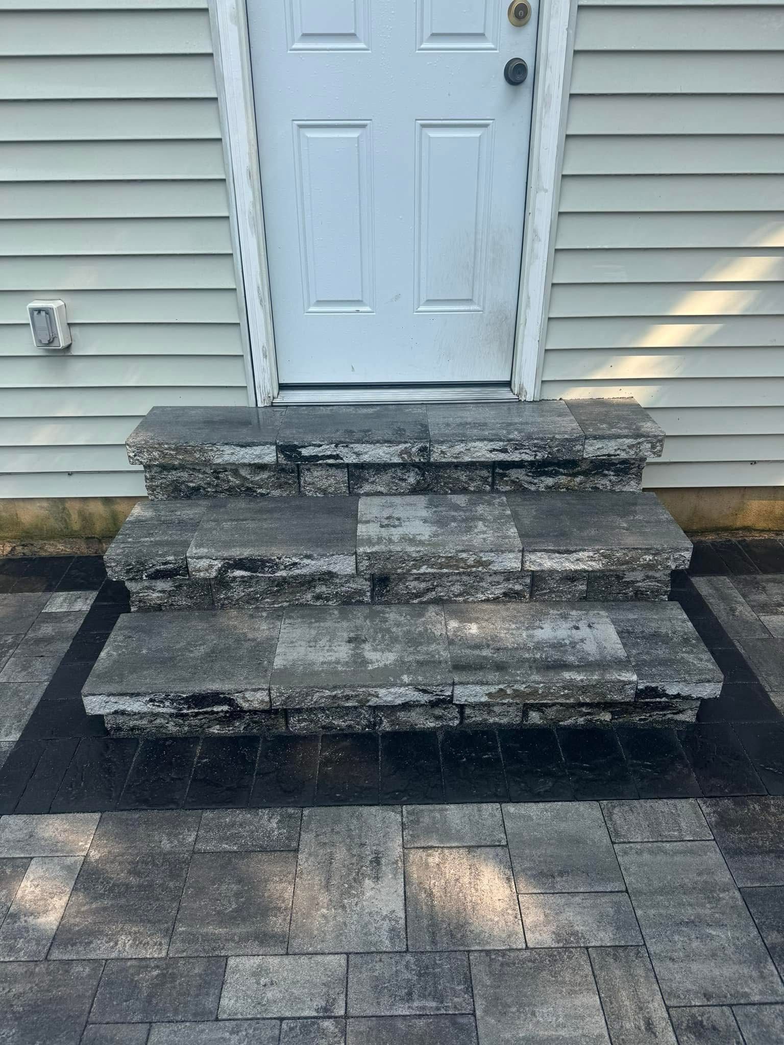 Worn concrete steps leading to a white front door on a beige-sided house.