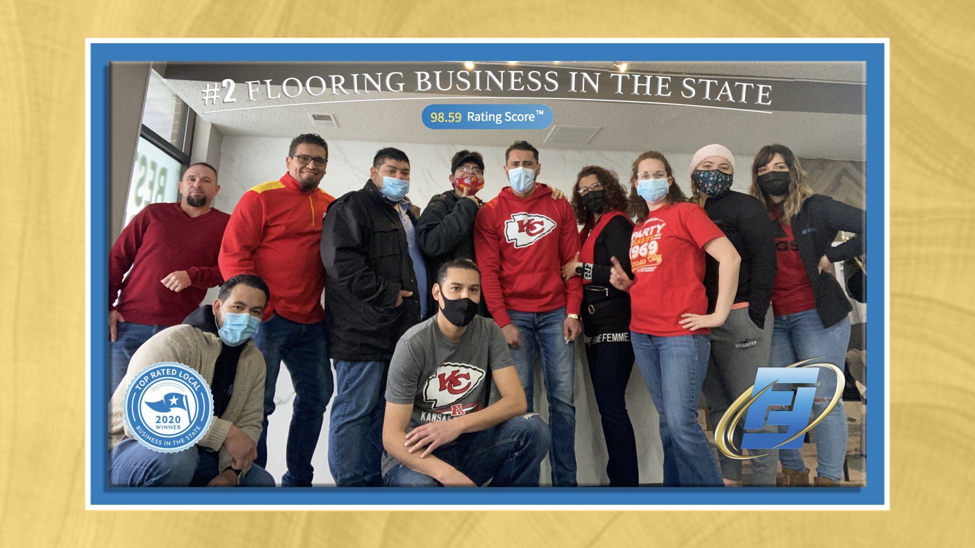 Group of masked people inside a building posing for a photo. They wear casual clothing and stand near a sign.