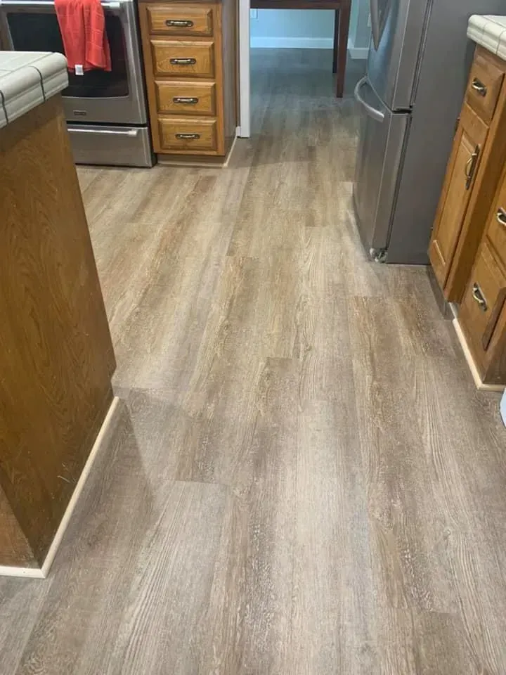 Kitchen with wood-look flooring. Cabinets and appliances are on either side of the room.