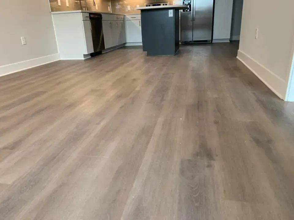 Light brown wood-look flooring in a modern kitchen with a gray island and white cabinets.