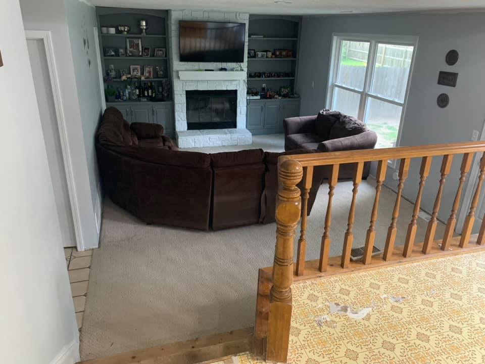 Living room with brown sectional, fireplace, built-ins, and stair railing.
