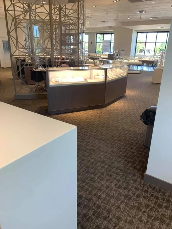 Interior of a jewelry store with display cases, a geometric structure, and carpeted floor.