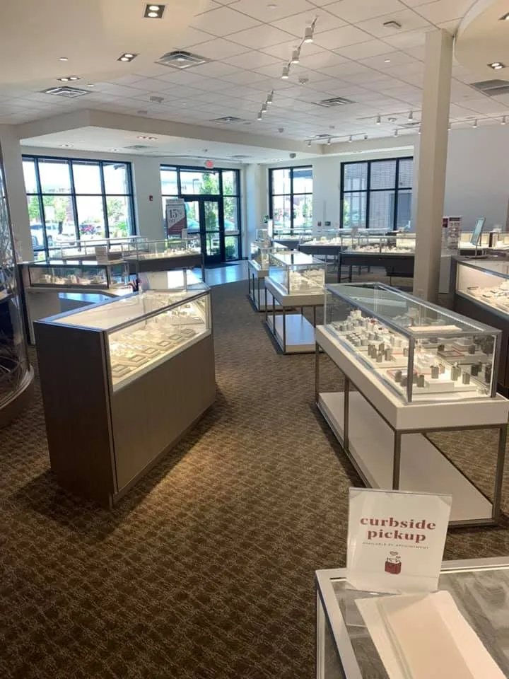 Jewelry store interior with display cases, carpet, and a curbside pickup sign.