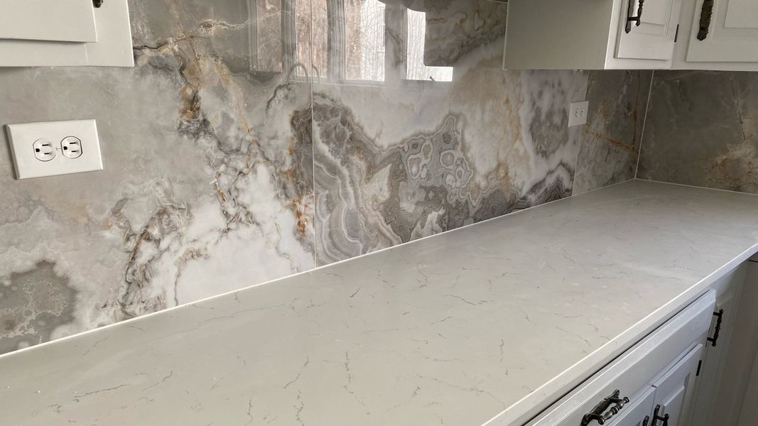 Countertop and backsplash with marbled pattern in a kitchen.