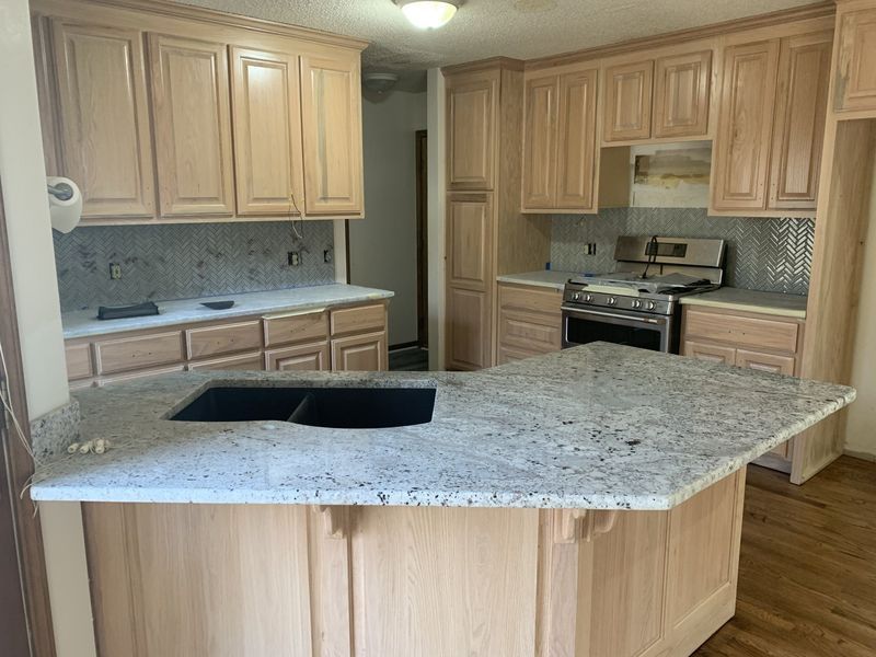 Kitchen with light wood cabinets, granite countertops, and a stove.