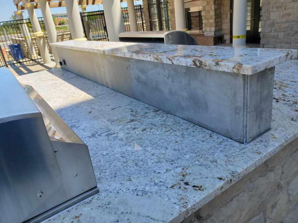Outdoor granite countertop with a gray concrete base.