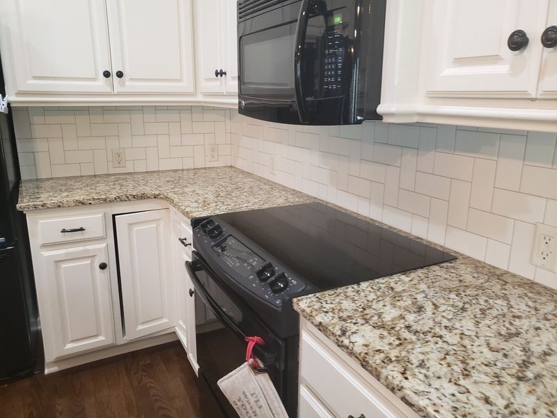 Kitchen with white cabinets, granite countertops, and black appliances.