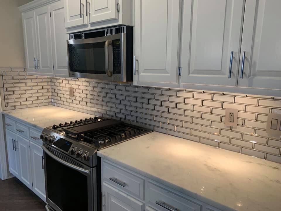 White kitchen with subway tile backsplash, stainless steel appliances, and white cabinets.