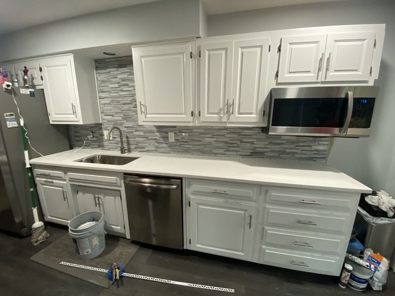 White kitchen cabinets, stainless steel appliances, and tiled backsplash in a renovated kitchen.