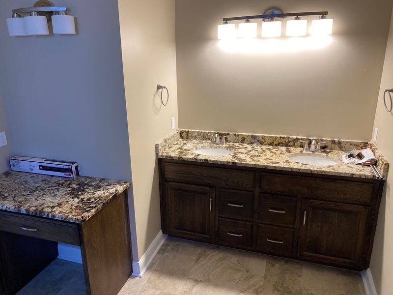 Bathroom with a double sink vanity, granite countertop, and additional vanity with matching countertop.
