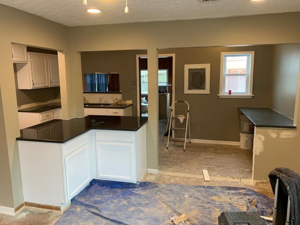 Kitchen remodel in progress: white cabinets, black countertops, olive green walls, open floor plan.