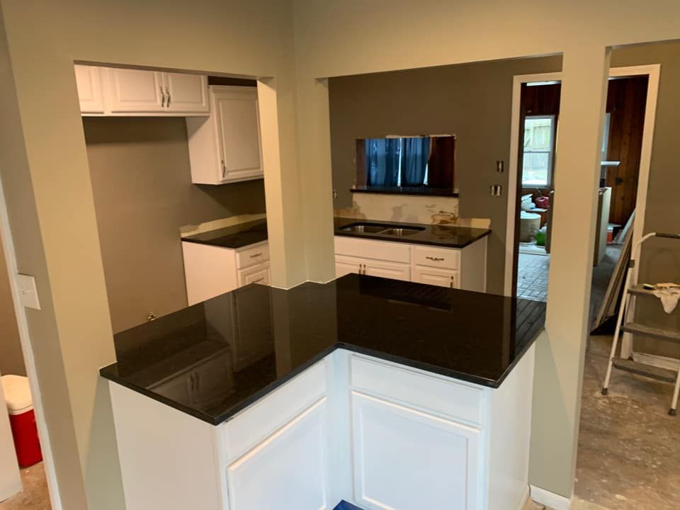 L-shaped kitchen with white cabinets, dark countertops, and open archways.