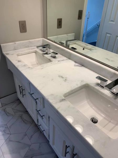 White marble bathroom vanity with two sinks, chrome fixtures, and a large mirror.