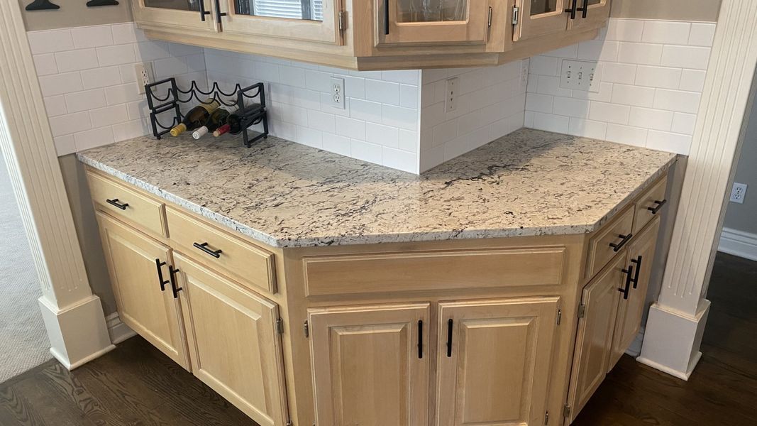 Kitchen corner with light wood cabinets, granite countertop, and wine rack.