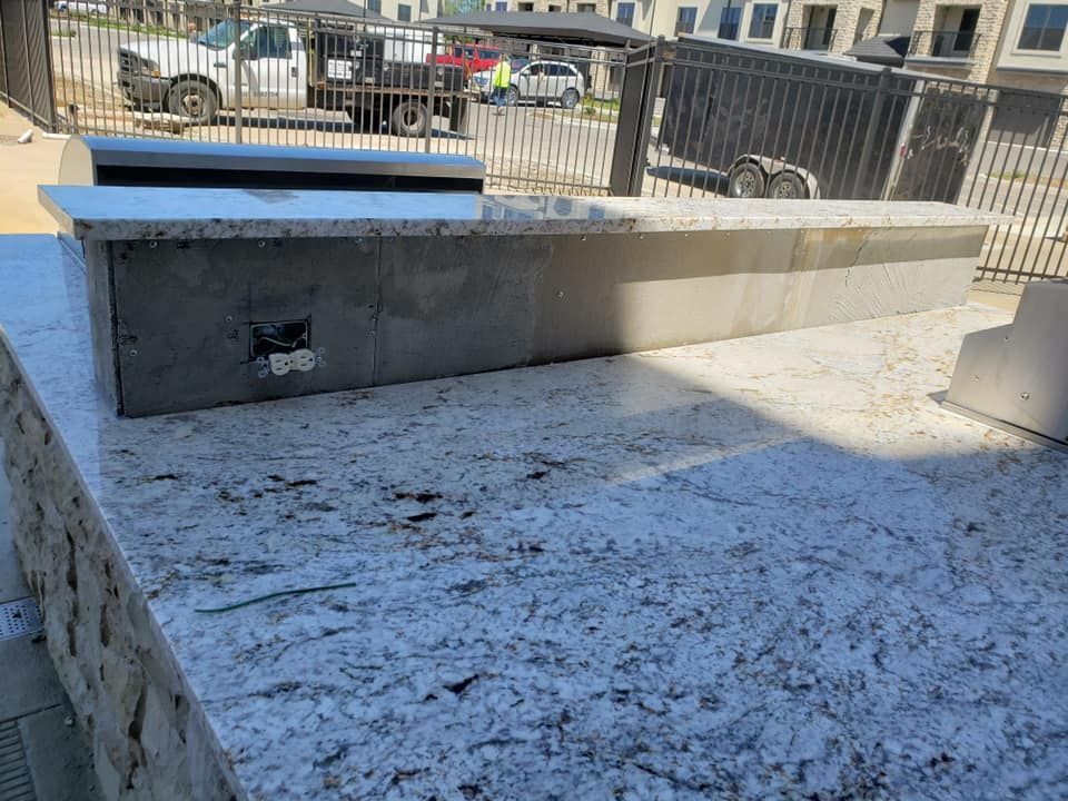 Outdoor kitchen countertop with a granite surface and concrete base.
