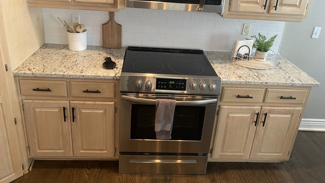 Kitchen with light wood cabinets, granite countertops, and stainless steel oven.