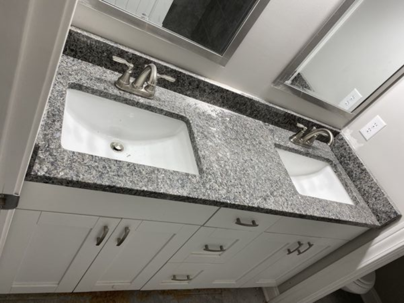 Bathroom vanity with two sinks, gray granite countertop, white cabinets, and mirrors.