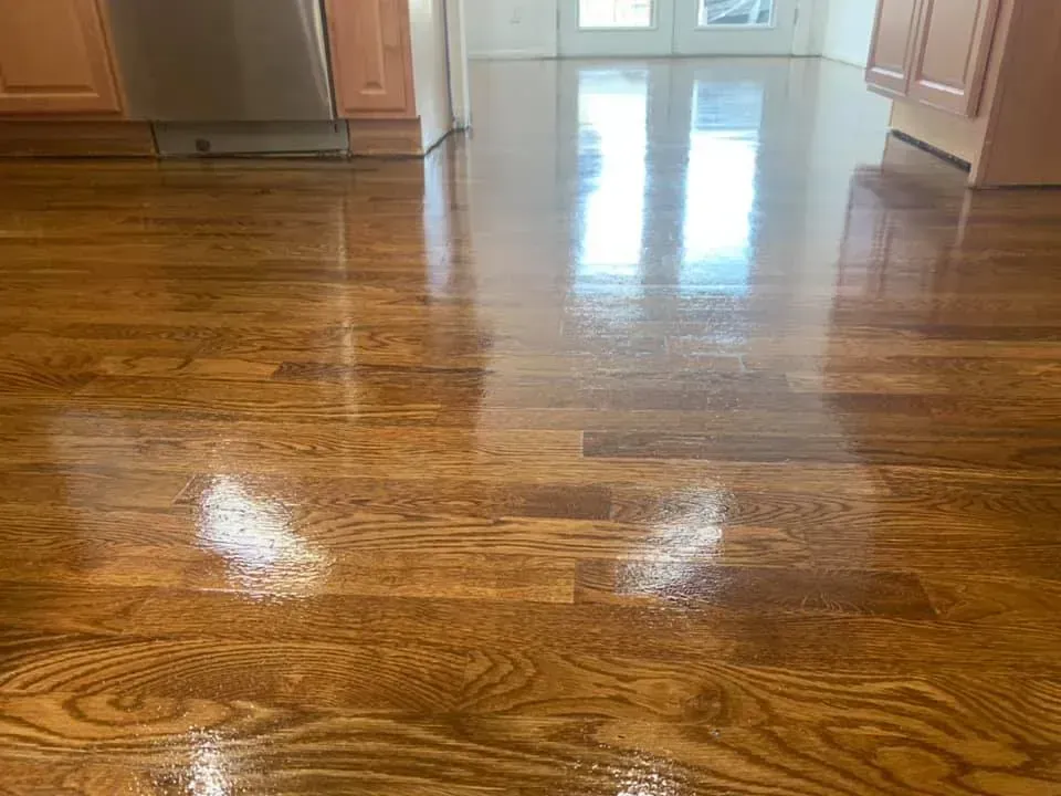 Shiny hardwood floor in a kitchen with reflections from a doorway and light.