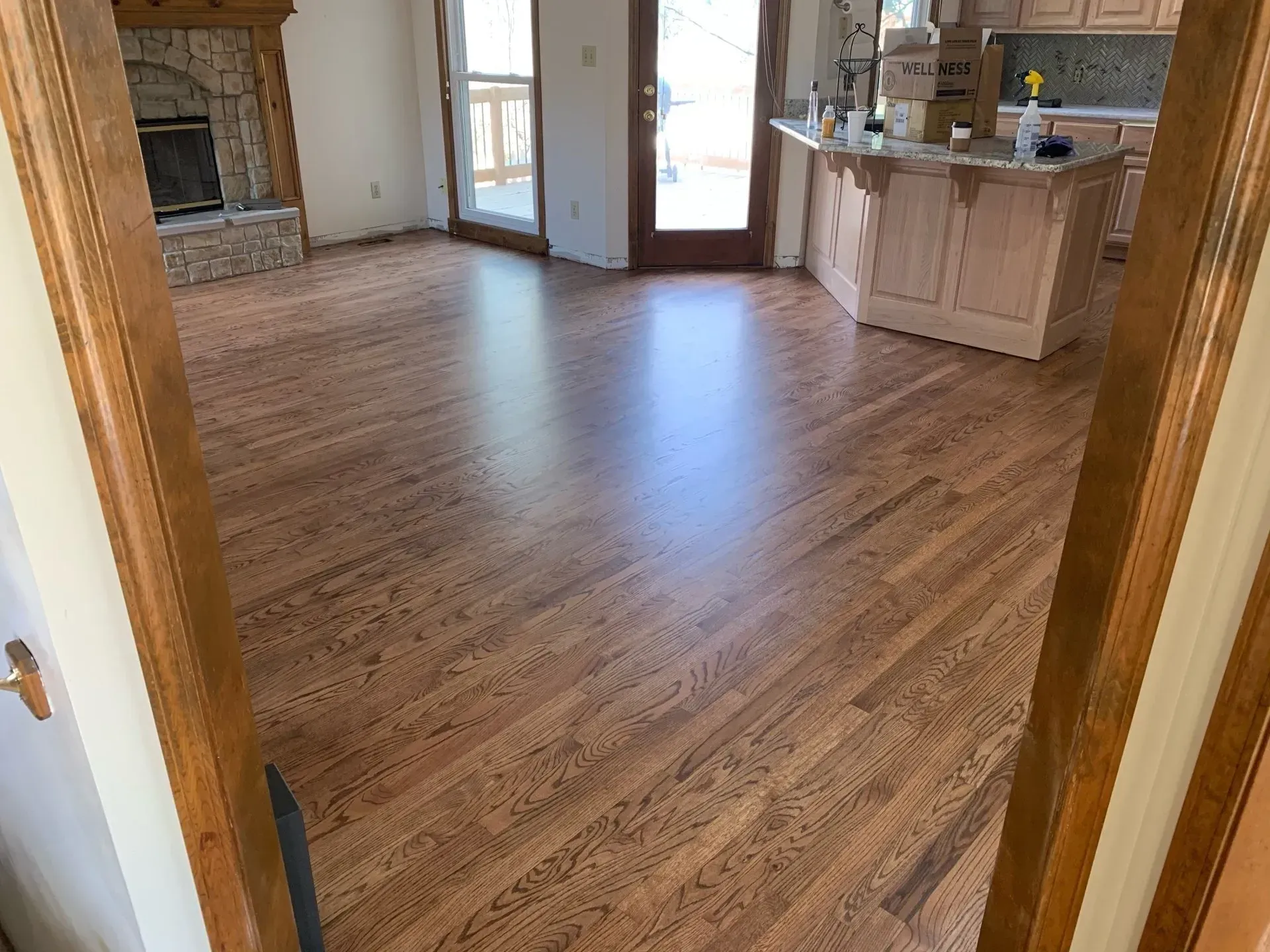 Hardwood floors in a house, leading to kitchen and fireplace.