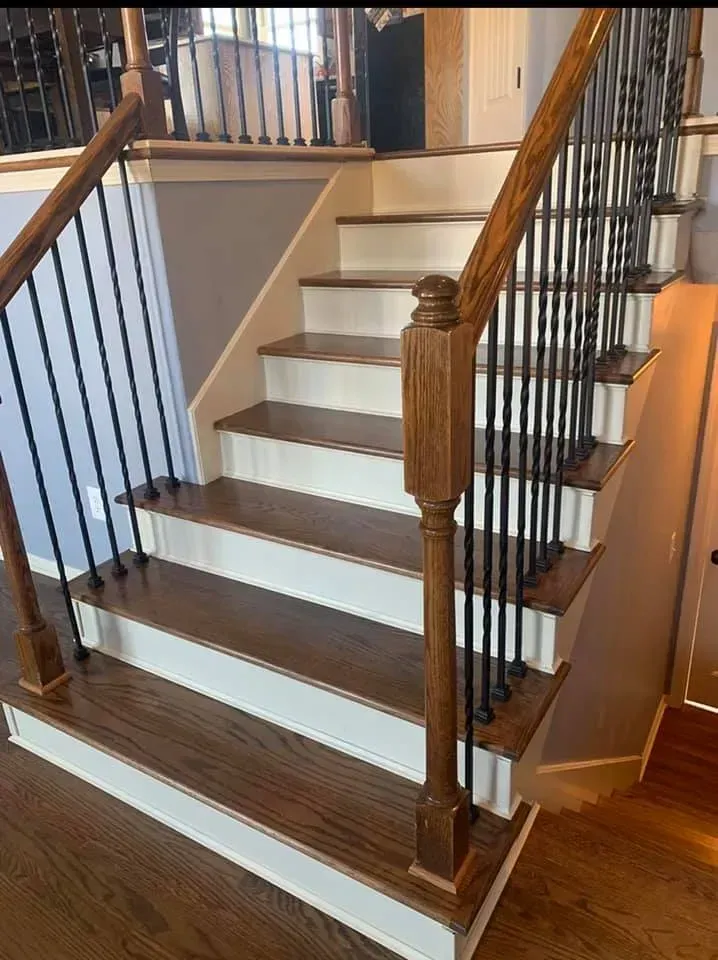 Wooden staircase with dark brown treads, white risers, and black iron balusters.