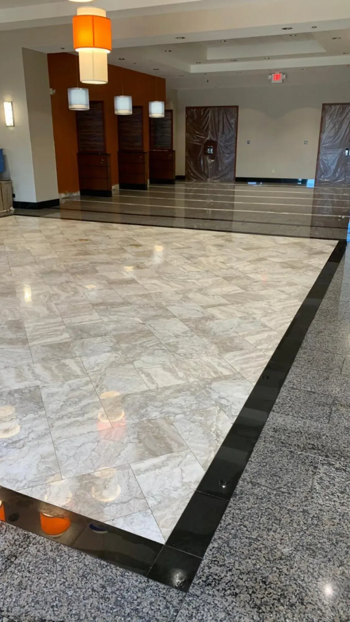 Large, polished lobby with marble and dark flooring, decorative lamps, and wood-paneled accents.