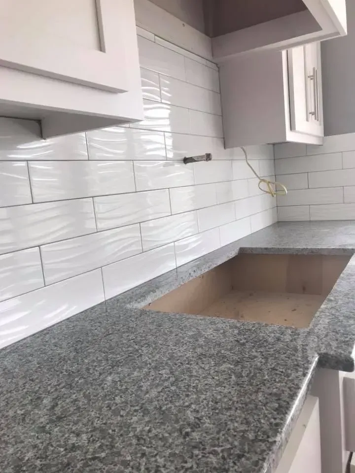 Kitchen countertop with granite surface, white cabinets and subway tile backsplash.