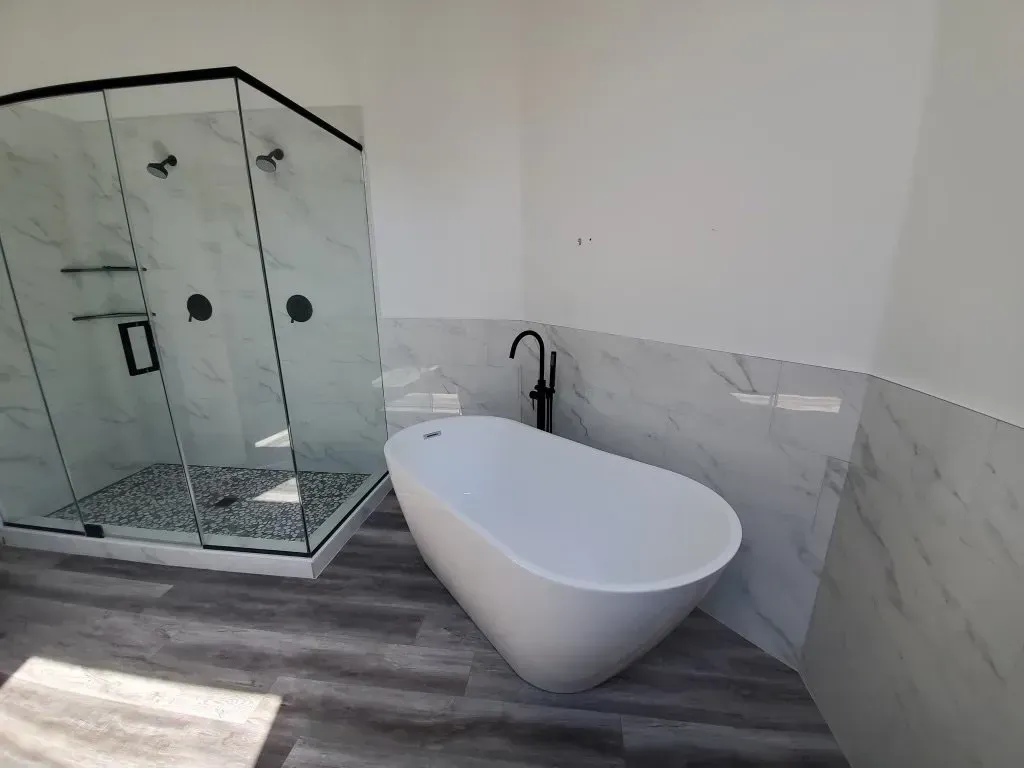 Modern bathroom with a white freestanding tub and glass shower.