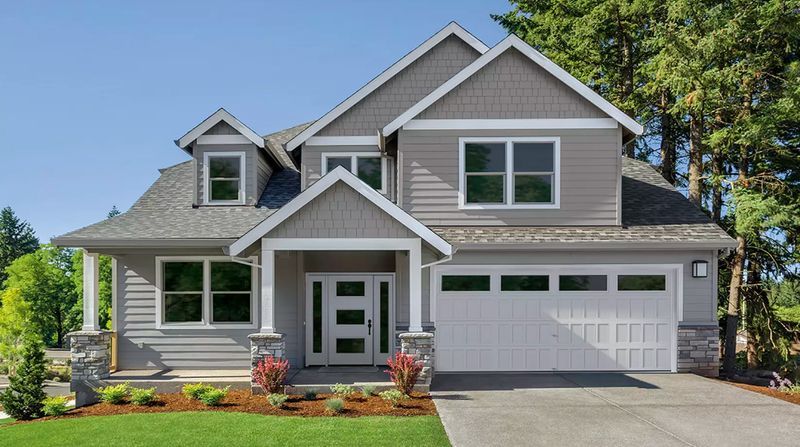 Suburban house with gray siding, white trim, front porch, and two-car garage on a sunny day