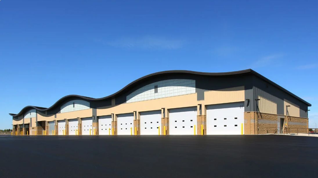 Large beige warehouse with multiple garage doors under a blue sky