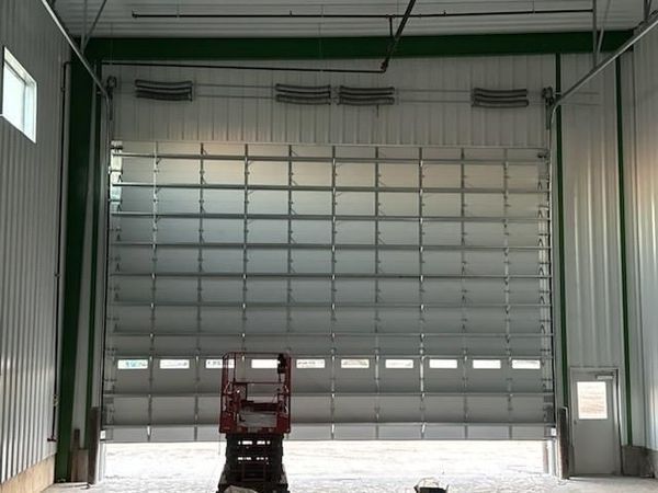 Empty industrial warehouse with a closed overhead garage door and a small lift at center