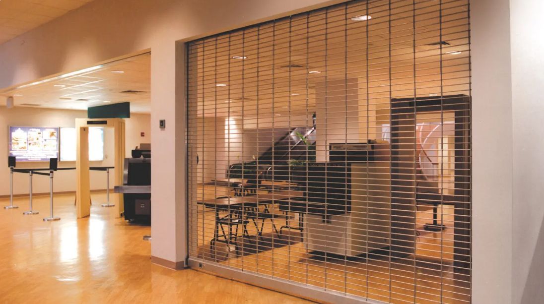 Modern office interior with wooden flooring and glass-walled meeting rooms behind a slatted partition